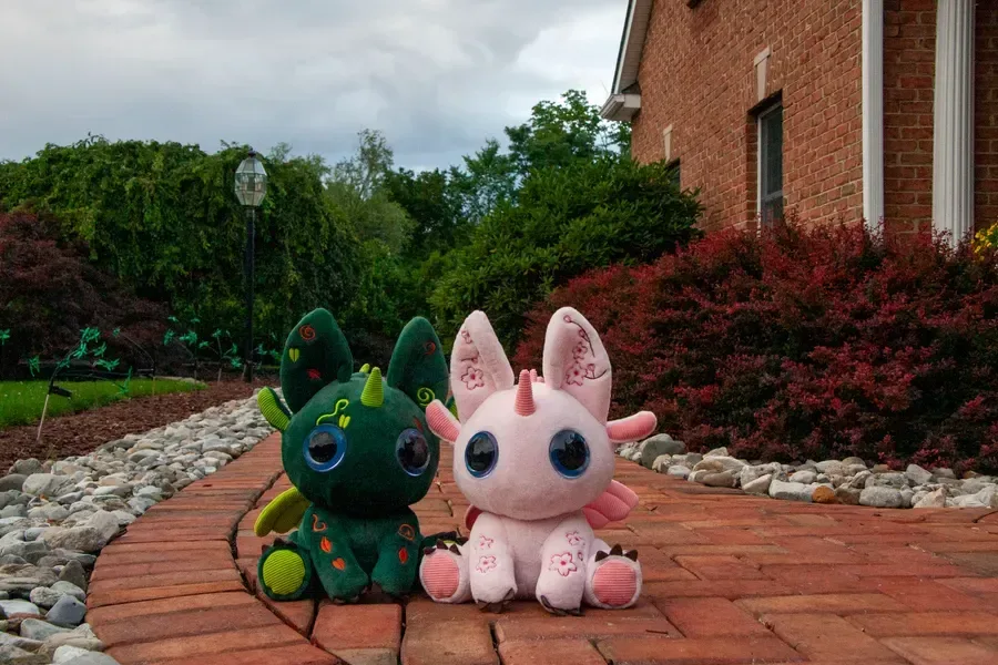 Two Bloom characters sitting together on a brick path outside a house.