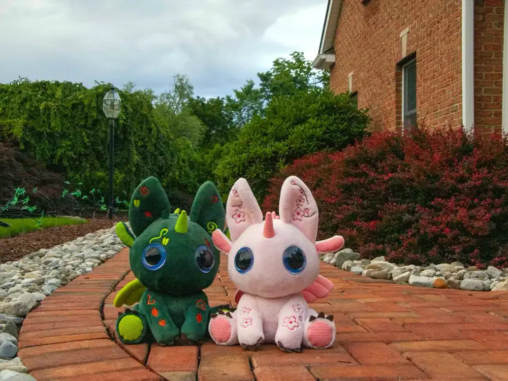 Two Bloom toys sitting together on a garden path.
