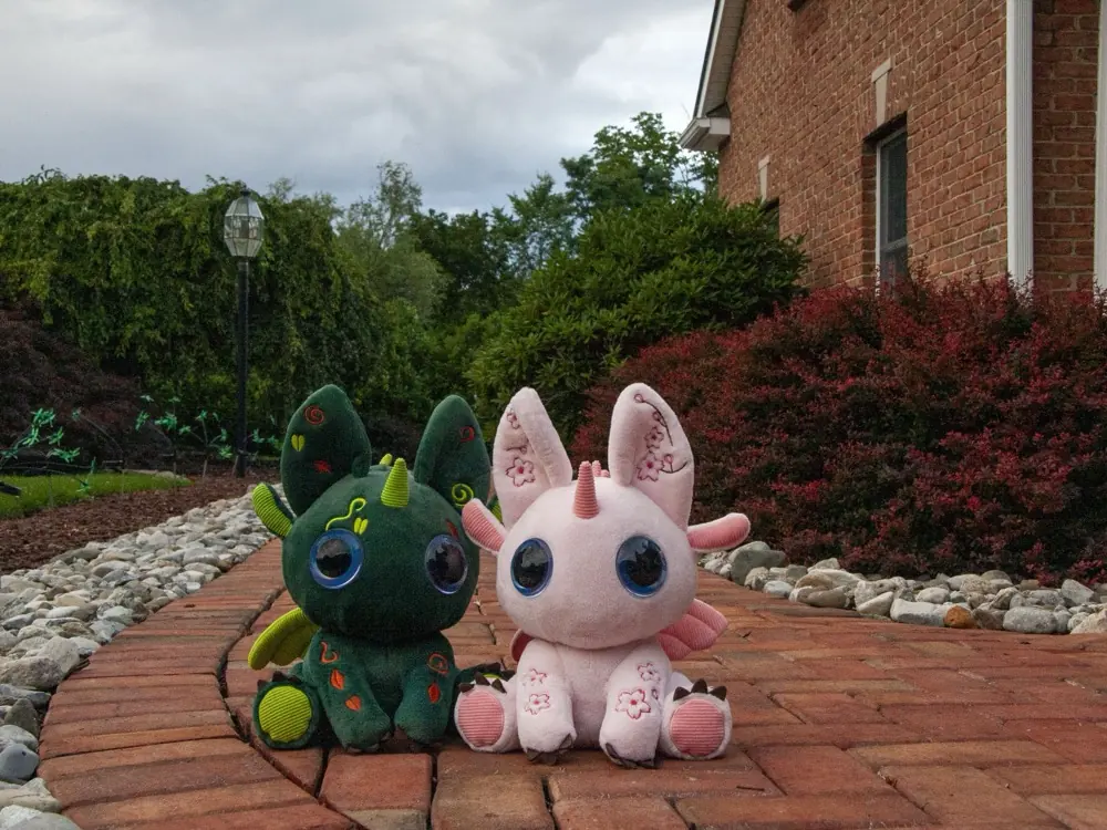 Two Bloom toys sitting together on a garden path.
