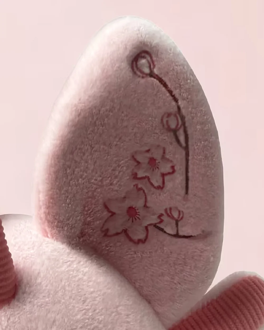 Close-up of pink Bloom's ear, showing embroidered blossoms.
