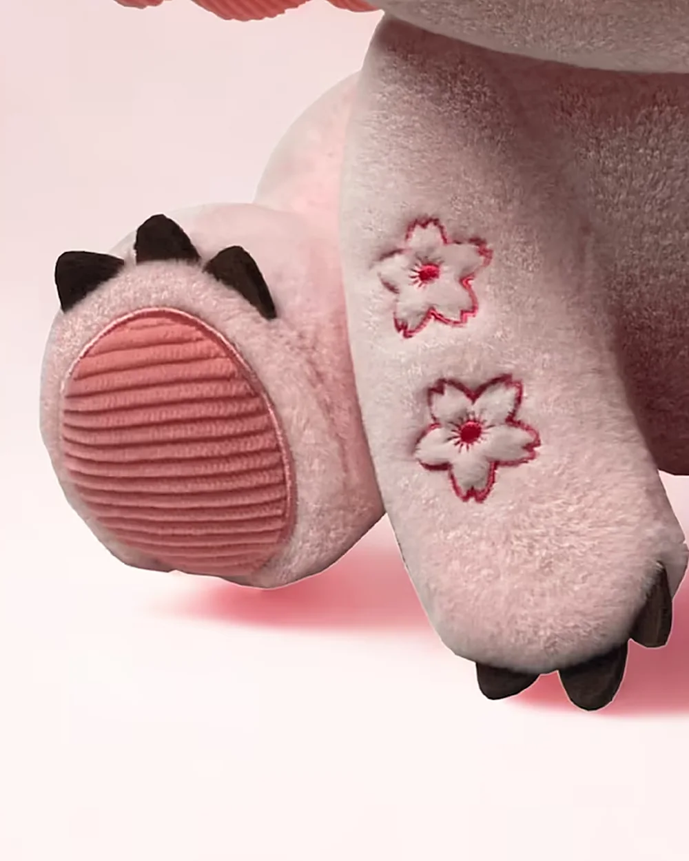 Close-up of pink Bloom's paw, showing a ribbed pad and embroidered markings.