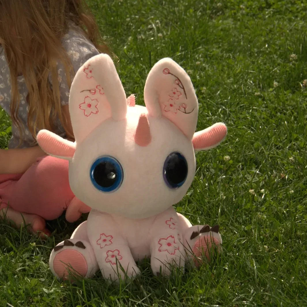 A girl sitting in the grass, busy with something in her hands, while Bloom sits beside her.